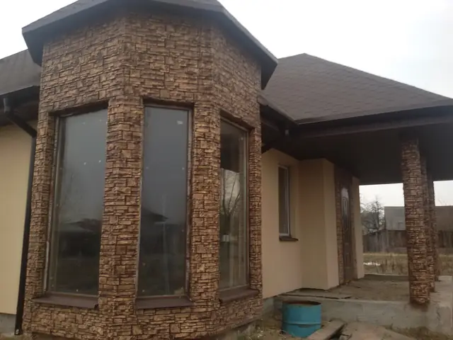 Octagonal bay window clad in brown stacked stone beneath a pointed roof