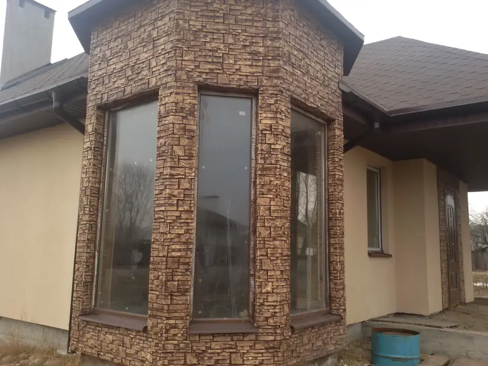 Two tall windows in a bay clad in rough stone