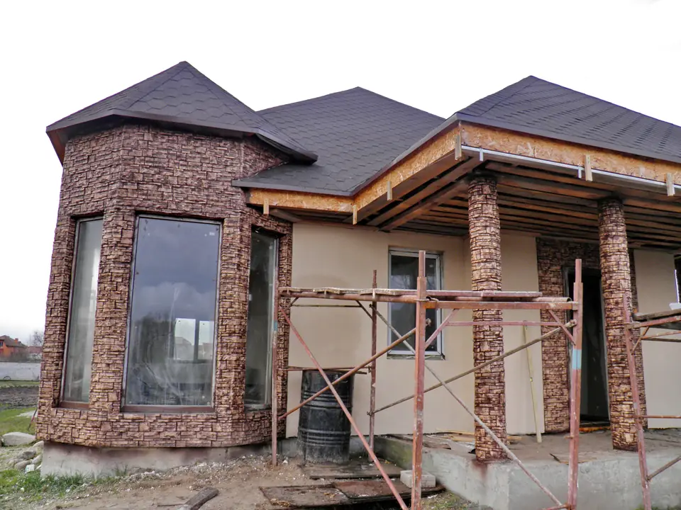 Bay window under construction, with scaffolding and stone-clad piers