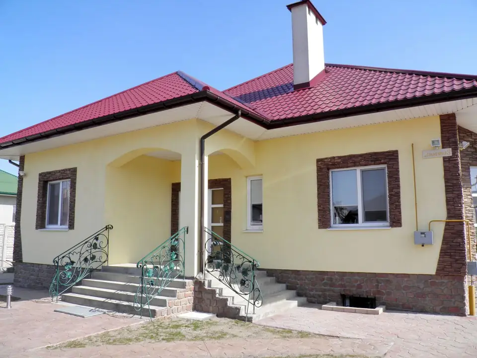 A house with a red roof, stone-effect window surrounds and a covered porch
