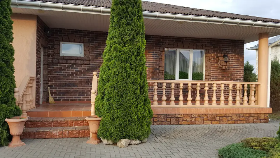 Veranda of a brick-effect house with a balustrade and a tiled floor