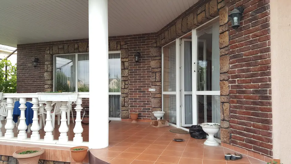 Covered terrace with a white balustrade and a round column against brick-effect walls