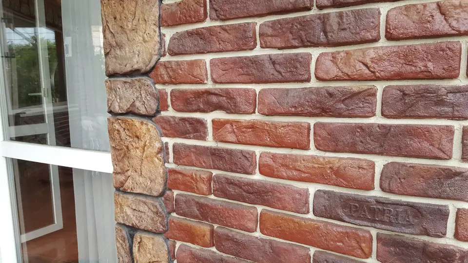 Close-up of brick-effect cladding with irregular stone around a window
