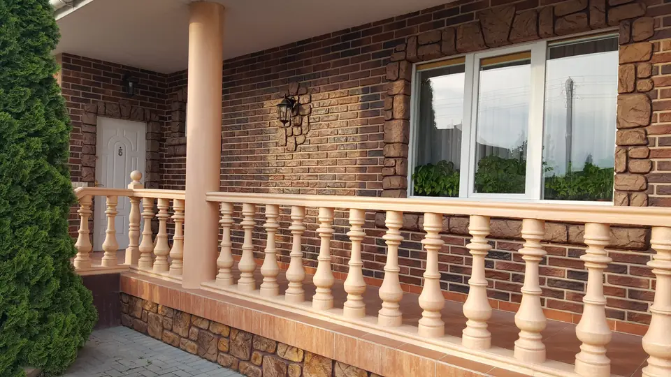 Terrace balustrade in warm peach tones against a dark brick-effect wall