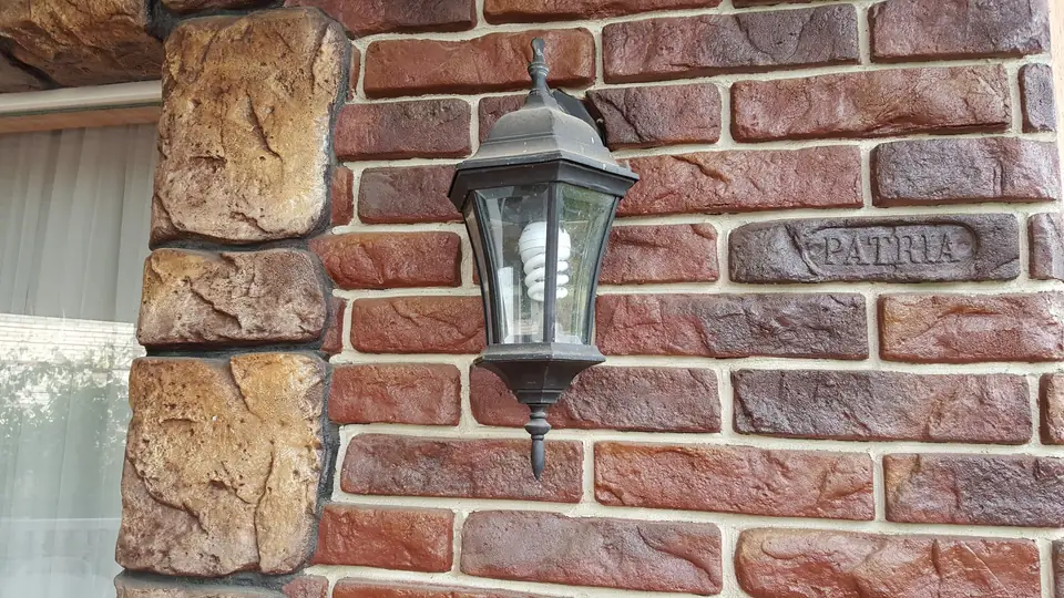 A wall lamp on a brick-effect wall with rough stone quoins