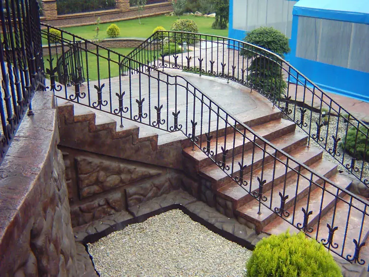 Stair with a wrought-iron railing in red-brown stone tones