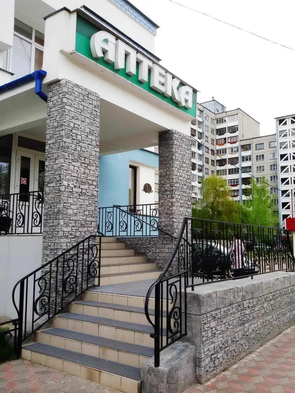 Entrance porch with stone-clad pillars and a wrought-iron balustrade