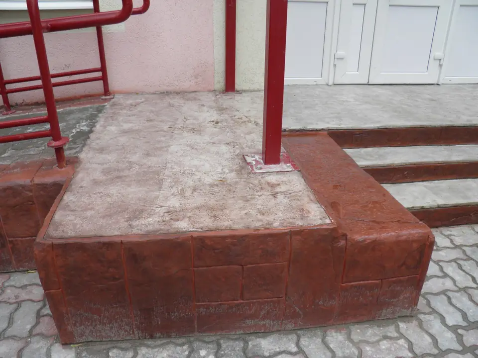 Raised entrance landing in red-brown stamped concrete
