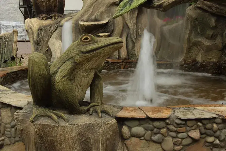 A frog and a water jet in a stone fountain basin