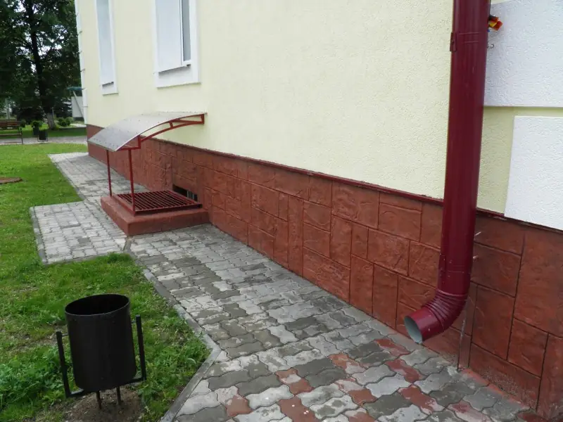 Red-brown plinth along the base of the building, with a flower bed