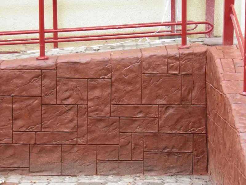 Plinth in a stamped block pattern with a red railing above