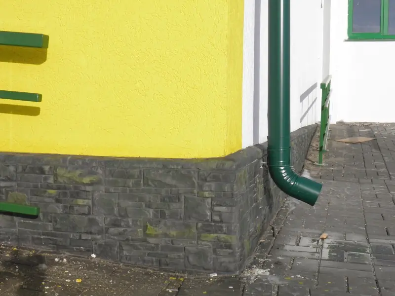 Corner of the plinth where the yellow wall meets the dark stone