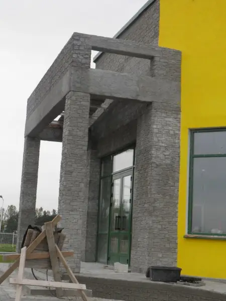 Portal frame in dark stacked stone against the yellow wall