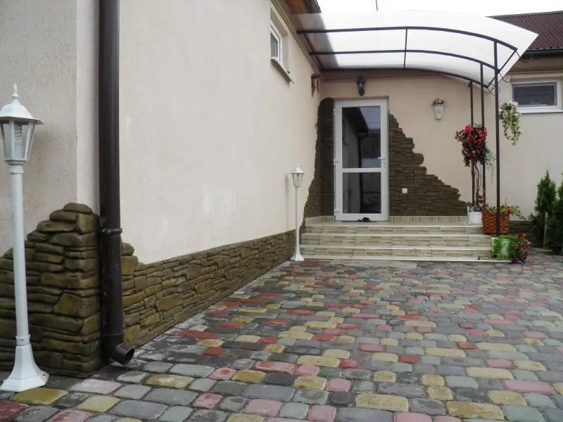 Entrance under a canopy, with a band of stone cladding rising up the white wall
