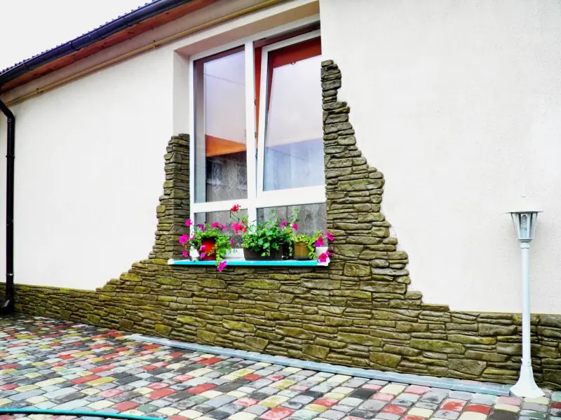 A window framed by irregular stone growing up from the plinth
