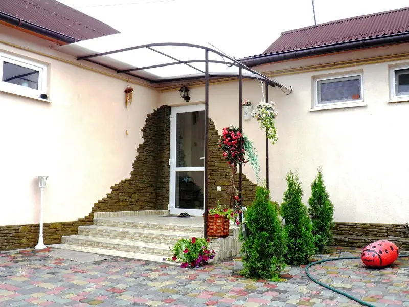 Entrance steps framed by stone cladding, with small conifers beside them