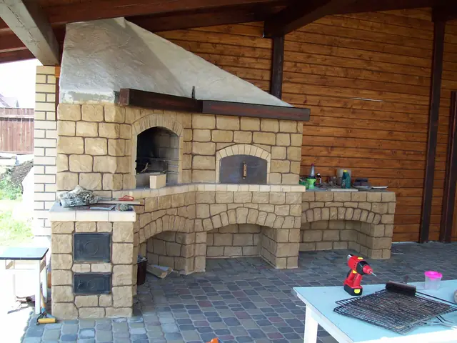 Outdoor kitchen under a timber roof with a stone-clad oven and hood