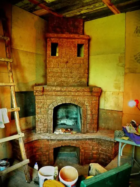 A tiled stove with a tall chimney in a colourful interior