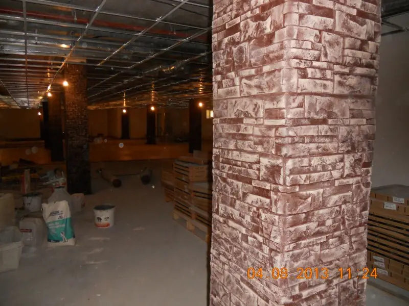 Stone-clad column in a hall under refurbishment, with pendant lights