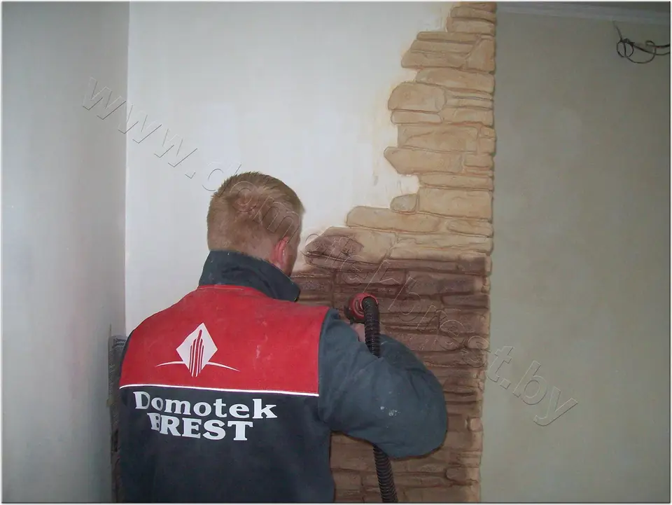 A craftsman shaping a stone texture on a wall