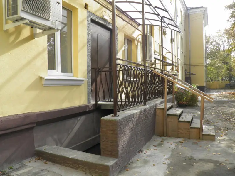 Entrance steps and railing on a yellow building with a stone-textured base