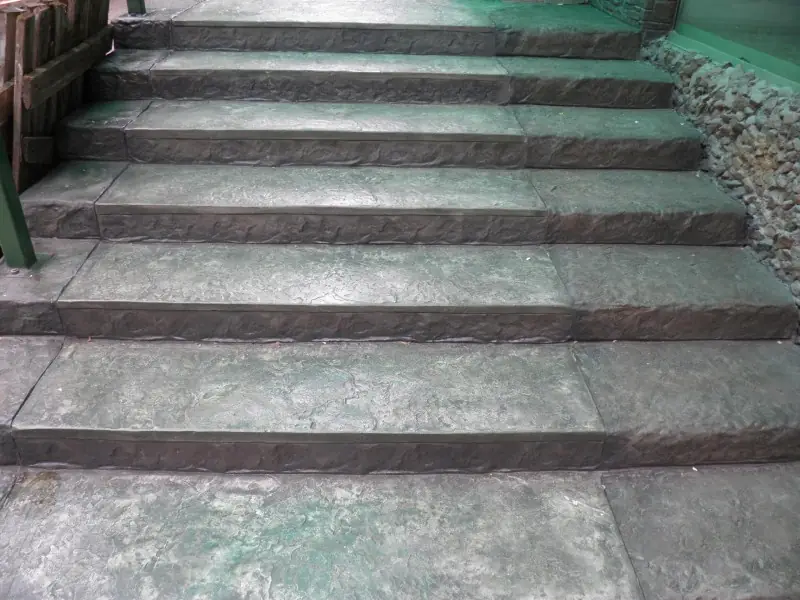 A wide entrance flight of stone-textured steps in pale grey-green