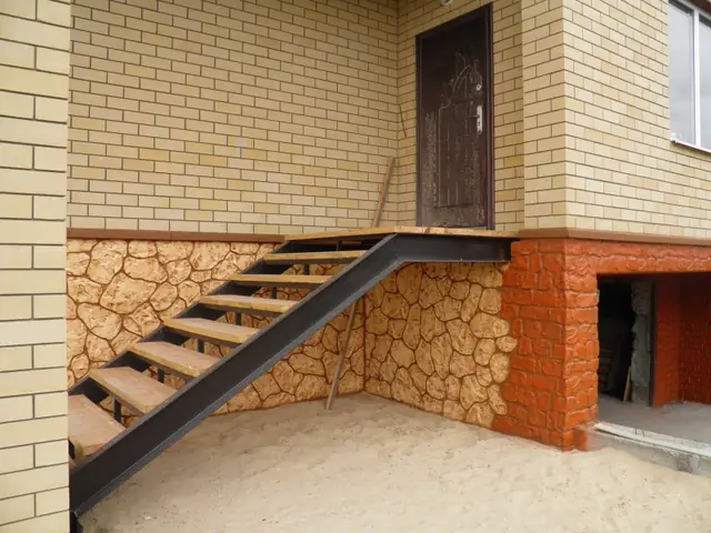 Stone-effect plinth in orange and sand tones with an entrance stair