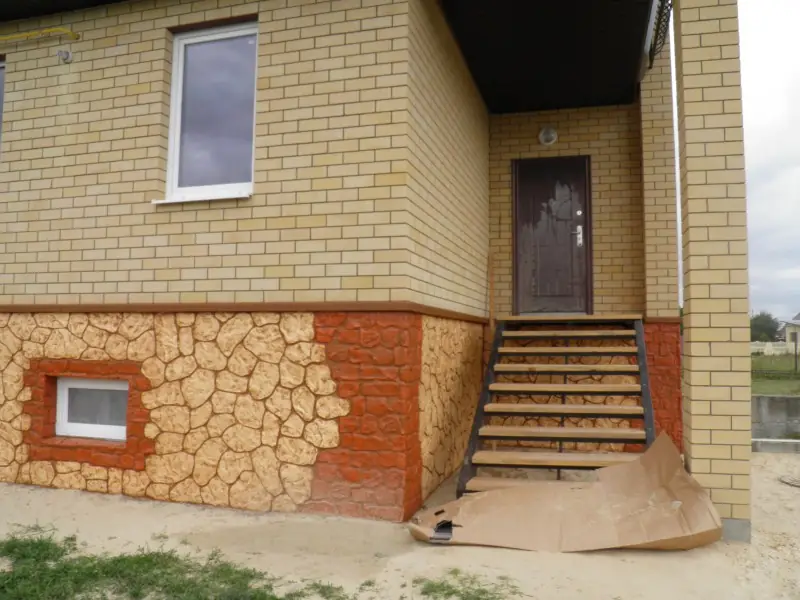 Entrance with steps and basement windows set into a flagstone-pattern plinth
