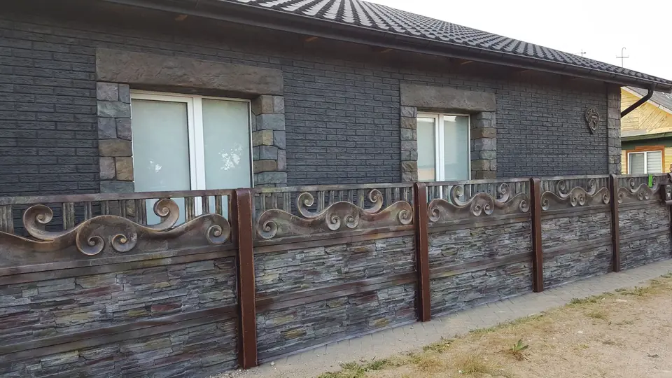 Fence with an ornamental scroll top rail between the house and the street
