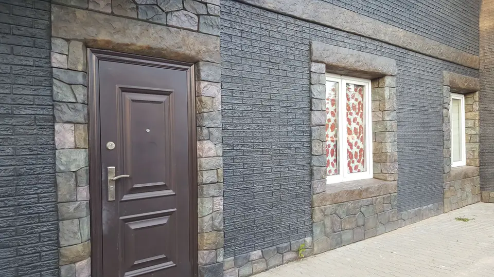 Front door and window in a dark brick-effect wall with stone surrounds