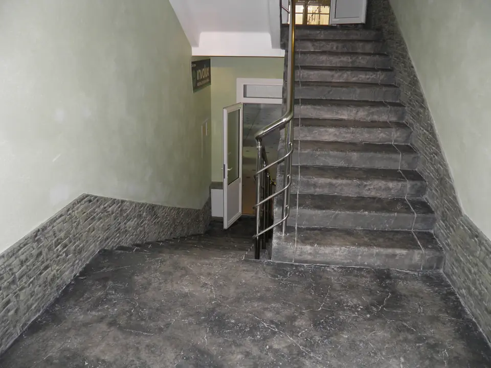 Stair landing and a flight of stone-textured steps beside a stone-clad wall
