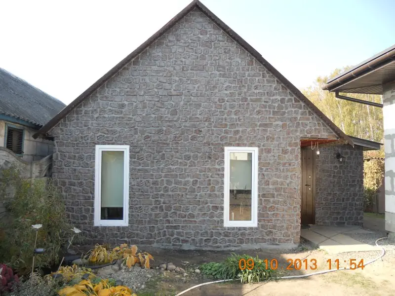 The finished outbuilding seen from the garden, a gable wall in rubble stone