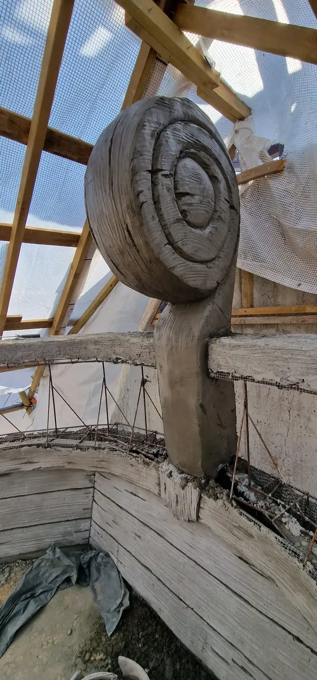 Hand-carved concrete scroll ornament on a raw structure of timber, mesh and reinforcing bars
