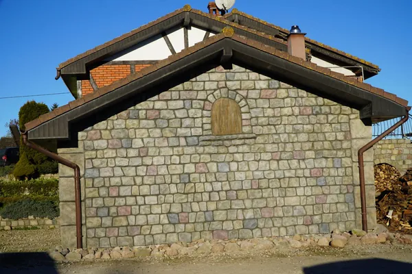 Giebel des Anbaus: Granit-Feldsteinmauerwerk in gemischten Naturtönen rund um ein Bogenfenster