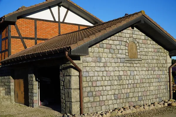 Der Anbau von der Ecke: Feldsteingiebel, dunkle Steinwand der Garage und massive Ecksteine