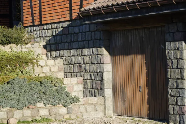 Garagenwand in dunklem Spaltstein neben der alten Granit-Stützmauer