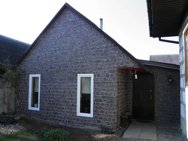The whole guest house: gable, windows and the entrance porch in hand-made rubble stone