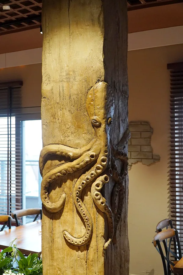 Octopus relief wrapping around the corner of an old timber column