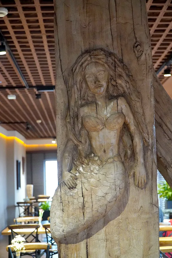 Mermaid relief: scales, long hair and weathered wood grain