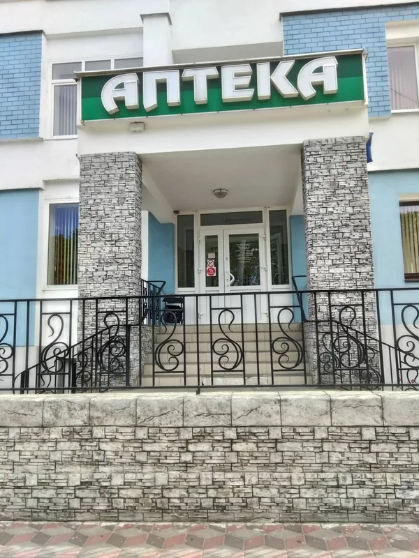 Pharmacy entrance: stone pillars under the sign and a stone retaining wall