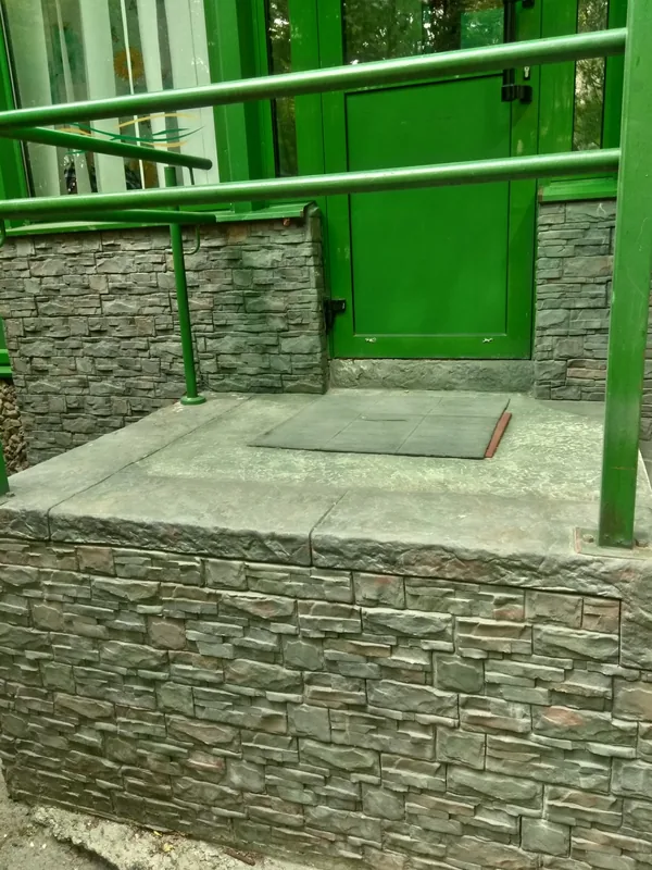 The landing in front of the door, on a layered stone plinth