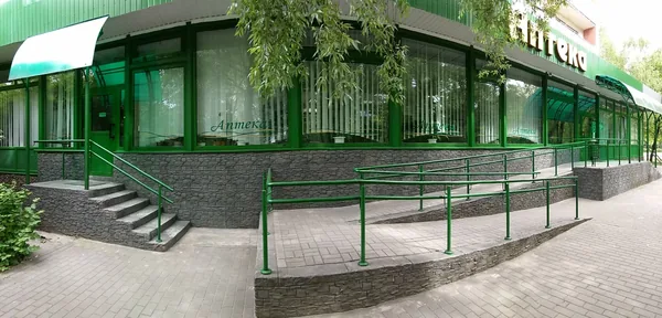 Pharmacy on a street corner: stone plinth under the shop windows, stairs and a long ramp