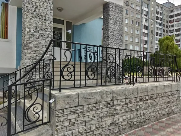 The retaining wall with its heavy coping, under a forged railing