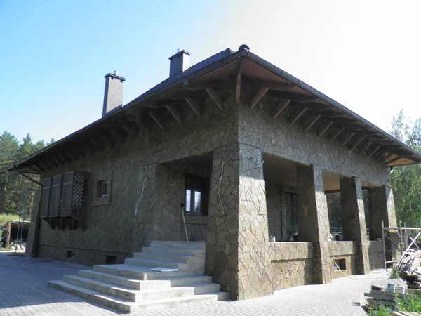 The house of the agro-estate with stone-clad walls and a covered terrace