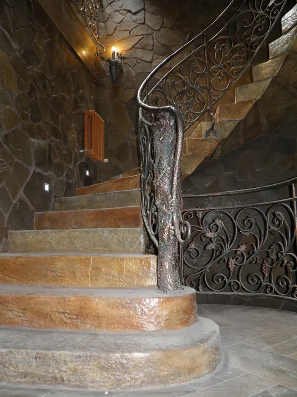The curved bottom steps and the forged tree-trunk newel post