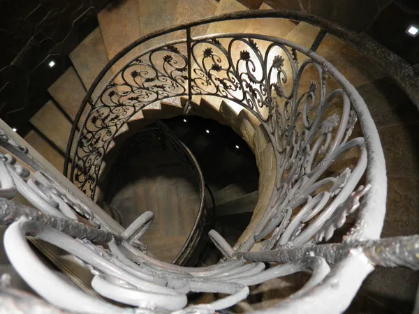 Looking down the stairwell: the stone spiral winding inside the forged railing