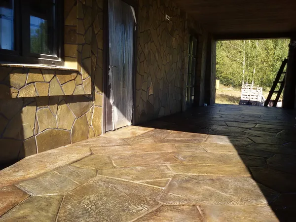 The covered terrace towards the forest, flagstone floor and walls