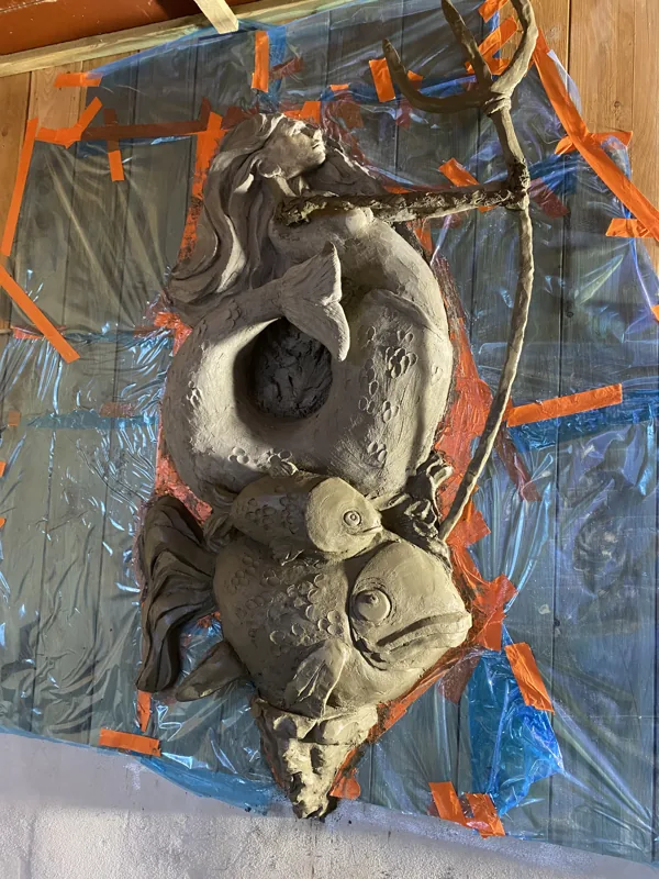 The same wall a few days later: a mermaid with a fish, modelled by hand